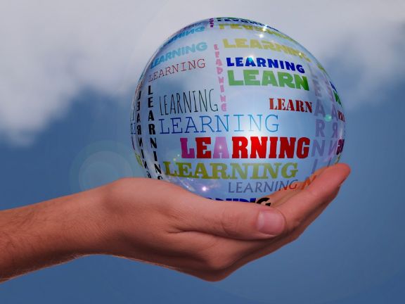 Mano sujetando una gran bola con palabras en ingles