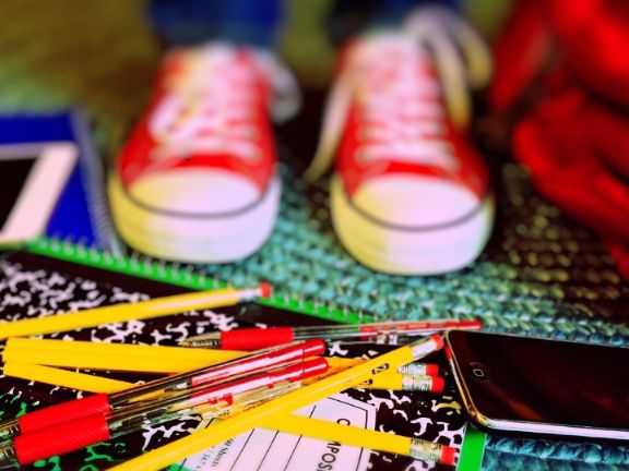 Objetos escolares por el suelo, bolígrafos, mochila, tablet, zapatillas deporte
