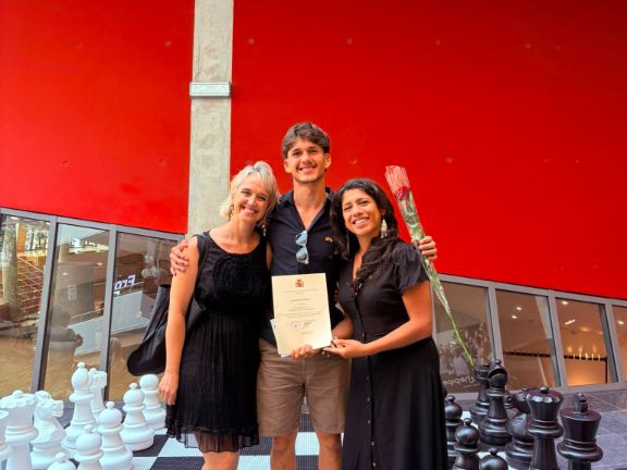 alumno posando con profesora y familiar, con diploma en mano