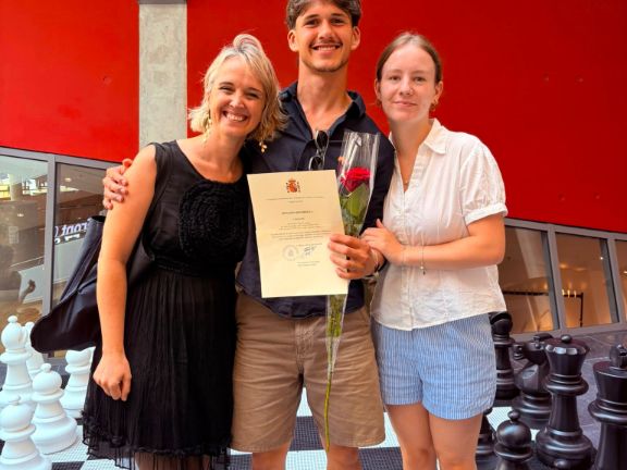 alumno posando con profesora y familiar y diploma en mano