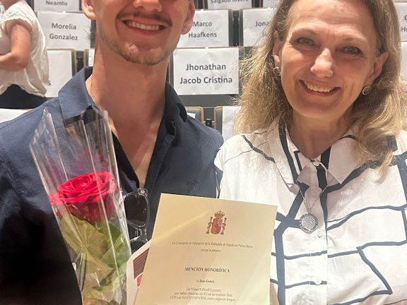 alumno posando con Embajadora y diploma en mano