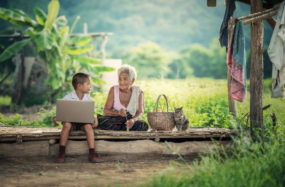 Fotografía de nieto con ordenador portátil y abuela en el campo