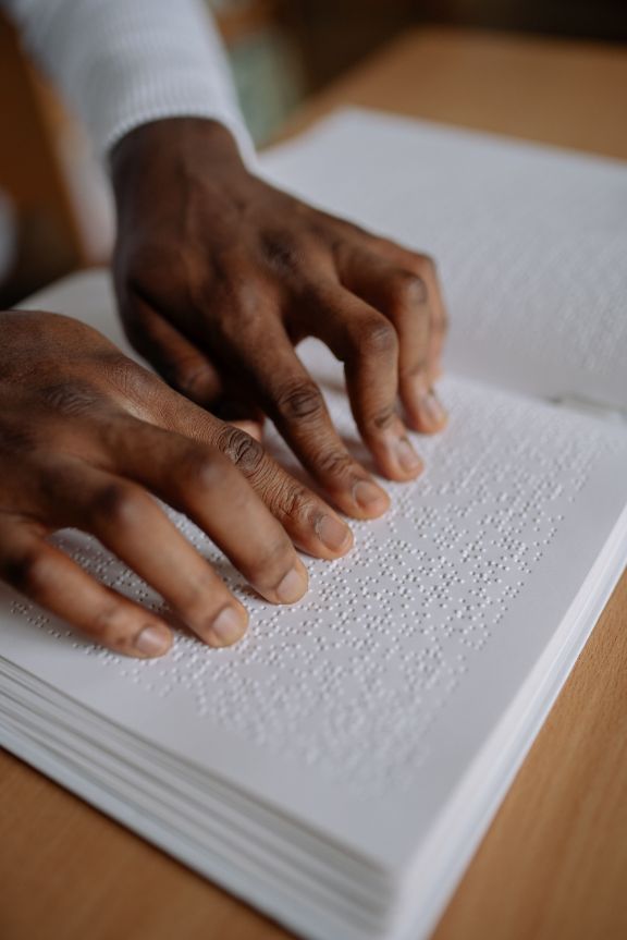 Foto de persona leyendo libro en braille