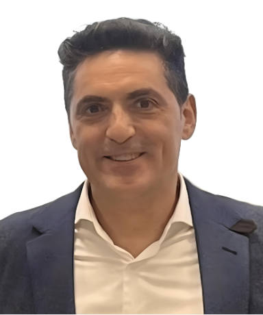 fotografía en medio plano de Agustín Reyes-Torres. Aparece con camisa beige y chaqueta de traje azul marino. Está sonriente, de unos 50 años