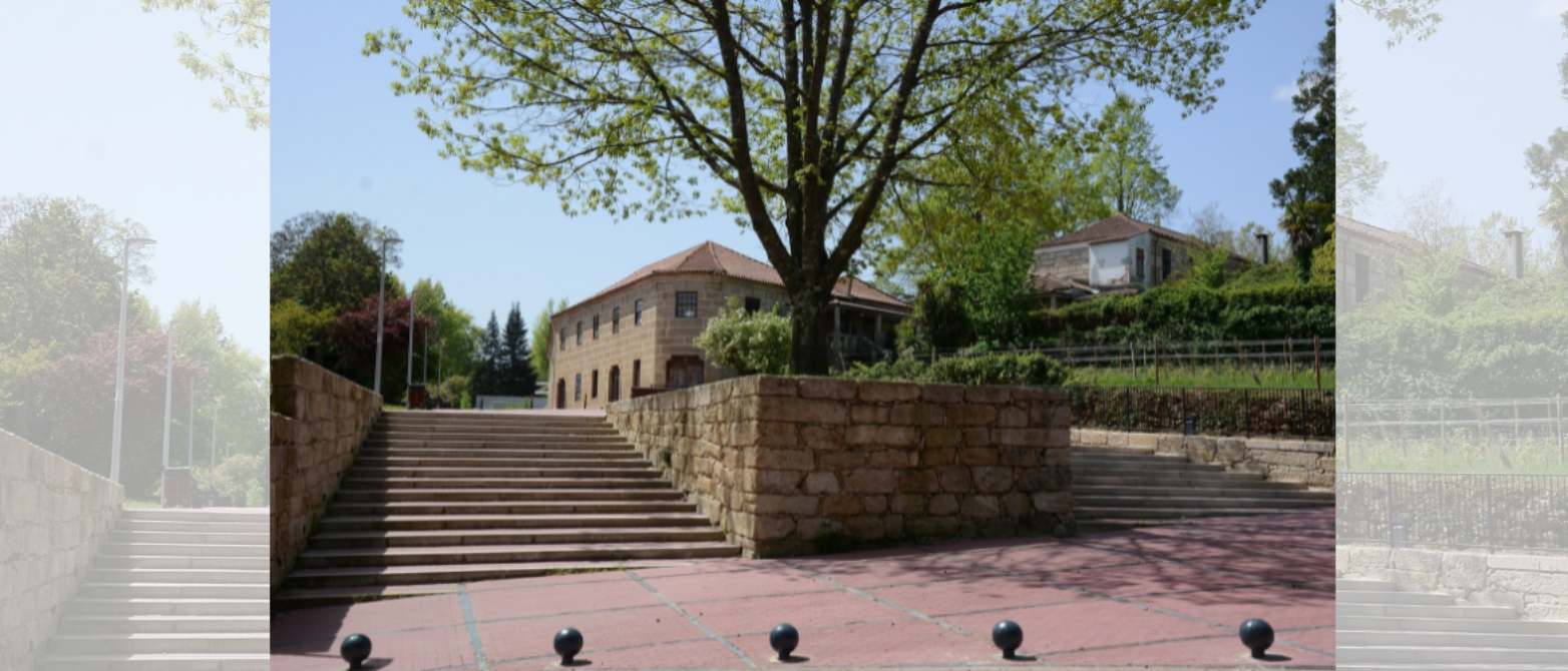 Escalinata de piedra flanqueada por muros de granito que conduce a edificios históricos del campus, con pavimento rojizo, bolardos esféricos y árboles