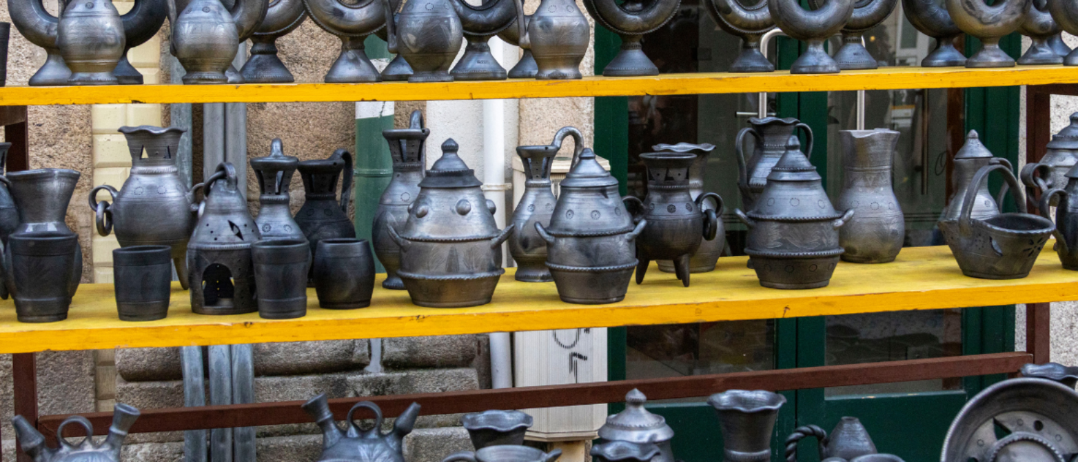 dos estanterías amarillas llenas de vasijas grises y negras. Parecen antiguas, de estilo románico